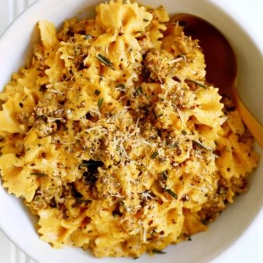 Cozy creamy pumpkin pasta served in a bowl with fresh herbs and parmesan cheese.
