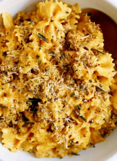 Cozy creamy pumpkin pasta served in a bowl with fresh herbs and parmesan cheese.
