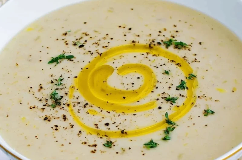 Bowl of creamy potato leek soup garnished with fresh herbs