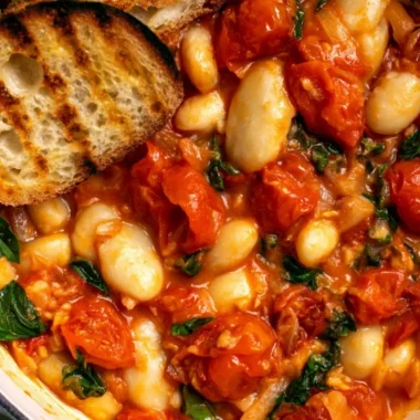 Creamy tomato basil butter beans stew in a bowl garnished with fresh basil.