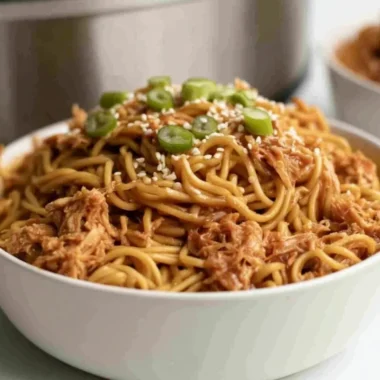 Crockpot Honey Garlic Chicken served over noodles with garnishes