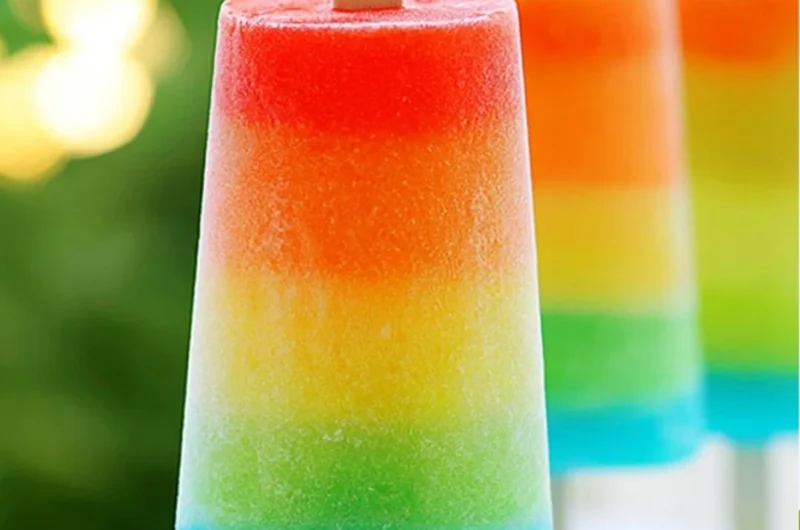 Colorful homemade rainbow popsicles in various fruity flavors