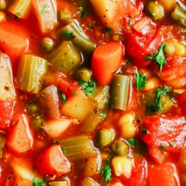Bowl of hearty vegetable soup with colorful vegetables and fresh herbs
