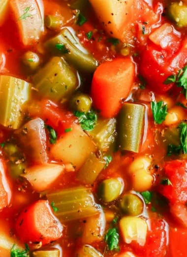Bowl of hearty vegetable soup with colorful vegetables and fresh herbs