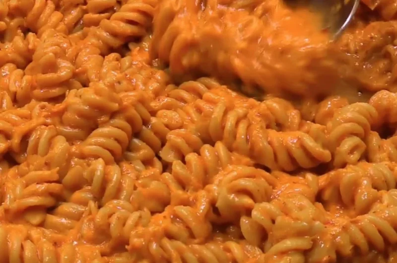High protein creamy tomato pasta served in a bowl with fresh basil and parmesan.