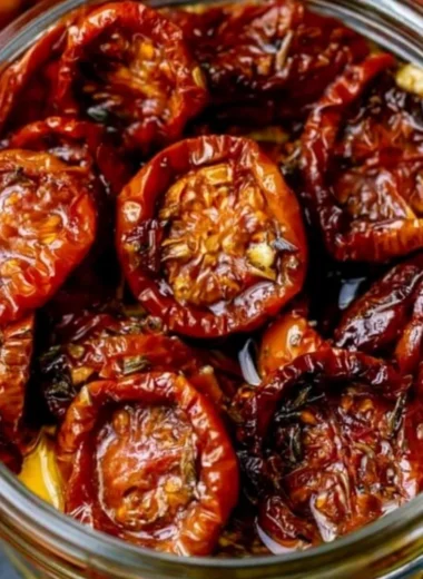 Homemade sun-dried cherry tomatoes in a glass jar with herbs