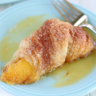Peach Cobbler Dumplings served in a dish with a scoop of vanilla ice cream