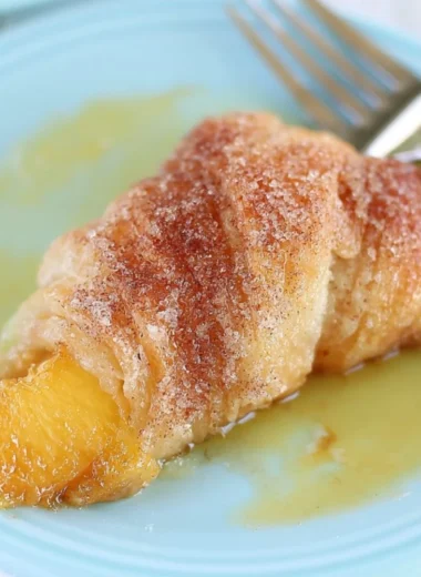 Peach Cobbler Dumplings served in a dish with a scoop of vanilla ice cream