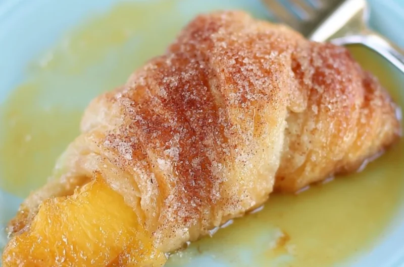 Peach Cobbler Dumplings served in a dish with a scoop of vanilla ice cream