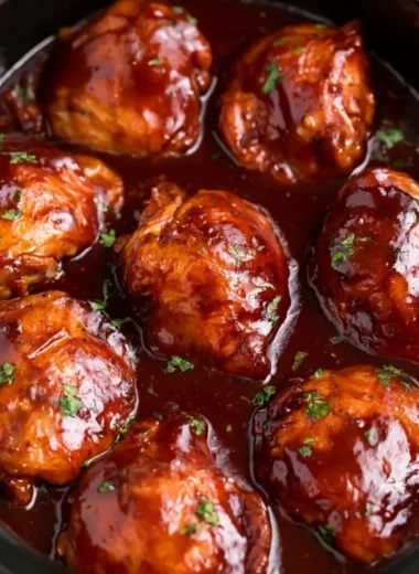 Slow cooker BBQ chicken thighs garnished with herbs and served on a plate