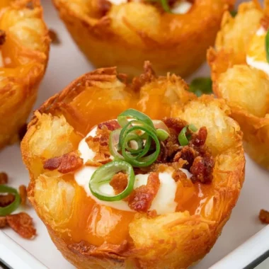 Loaded tater tot cups filled with gooey cheese, perfect for a party appetizer.